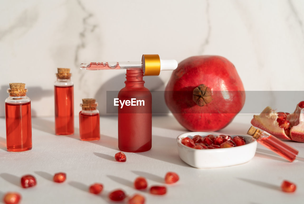 red, food and drink, food, fruit, healthy eating, produce, bottle, wellbeing, pomegranate, indoors, container, apple, no people, studio shot, healthcare and medicine, freshness, apple - fruit, vitamin, peach, soft drink, medicine, plant, still life, nutritional supplement, drink, seed
