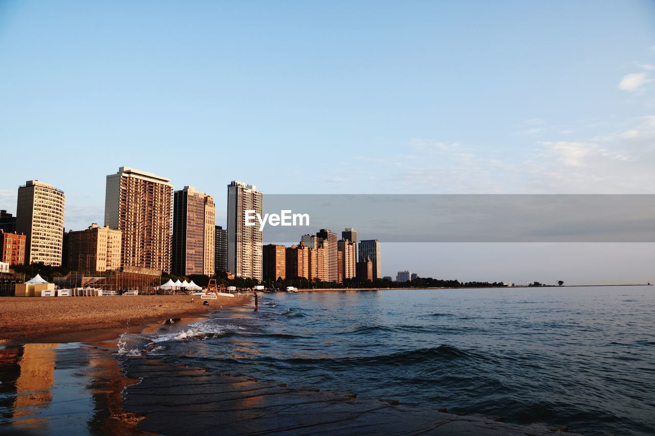 Sea by cityscape against sky