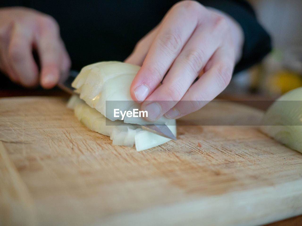 CLOSE-UP OF HAND HOLDING ICE CREAM ON CUTTING BOARD