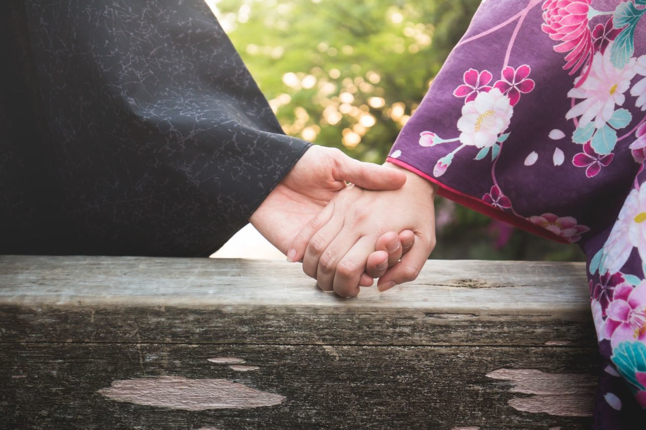 Close-up of couple holding hands on wood