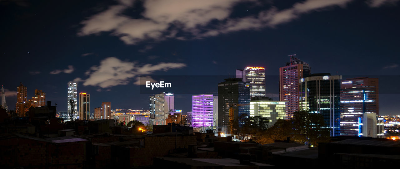 Illuminated buildings in city against sky at night