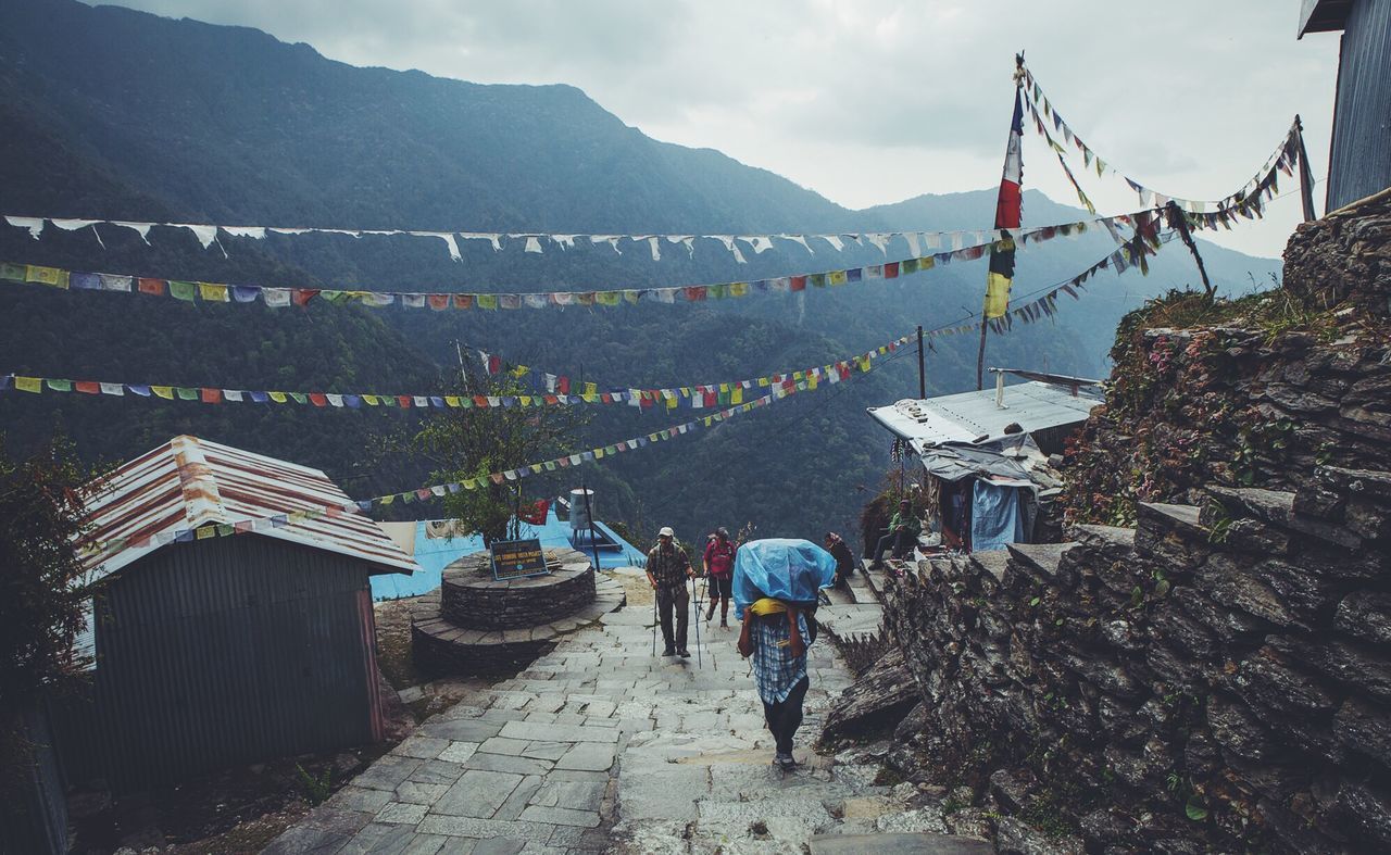 High angle view of people walking on pathway amidst houses against mountains