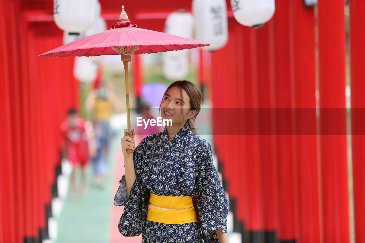 Woman in kimono walking into at the shrine, in japanese garden.