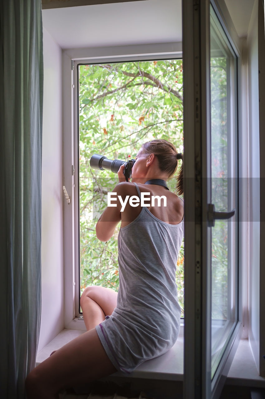 Woman looking through window at home