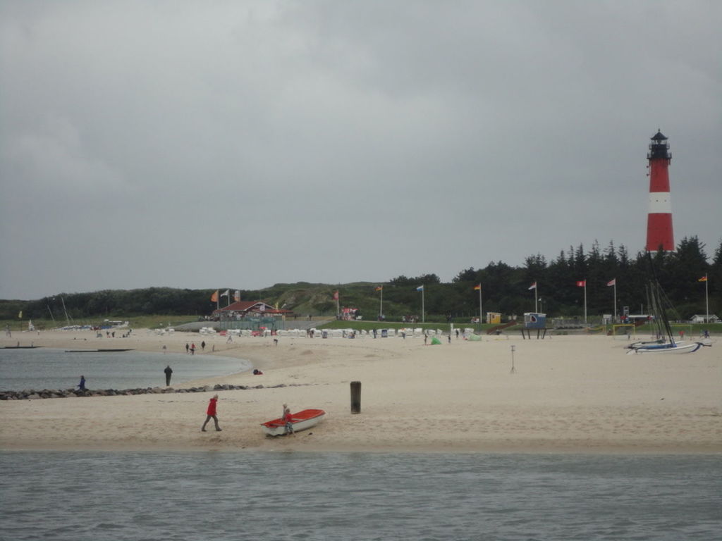 PEOPLE ON BEACH BY LIGHTHOUSE AGAINST SKY
