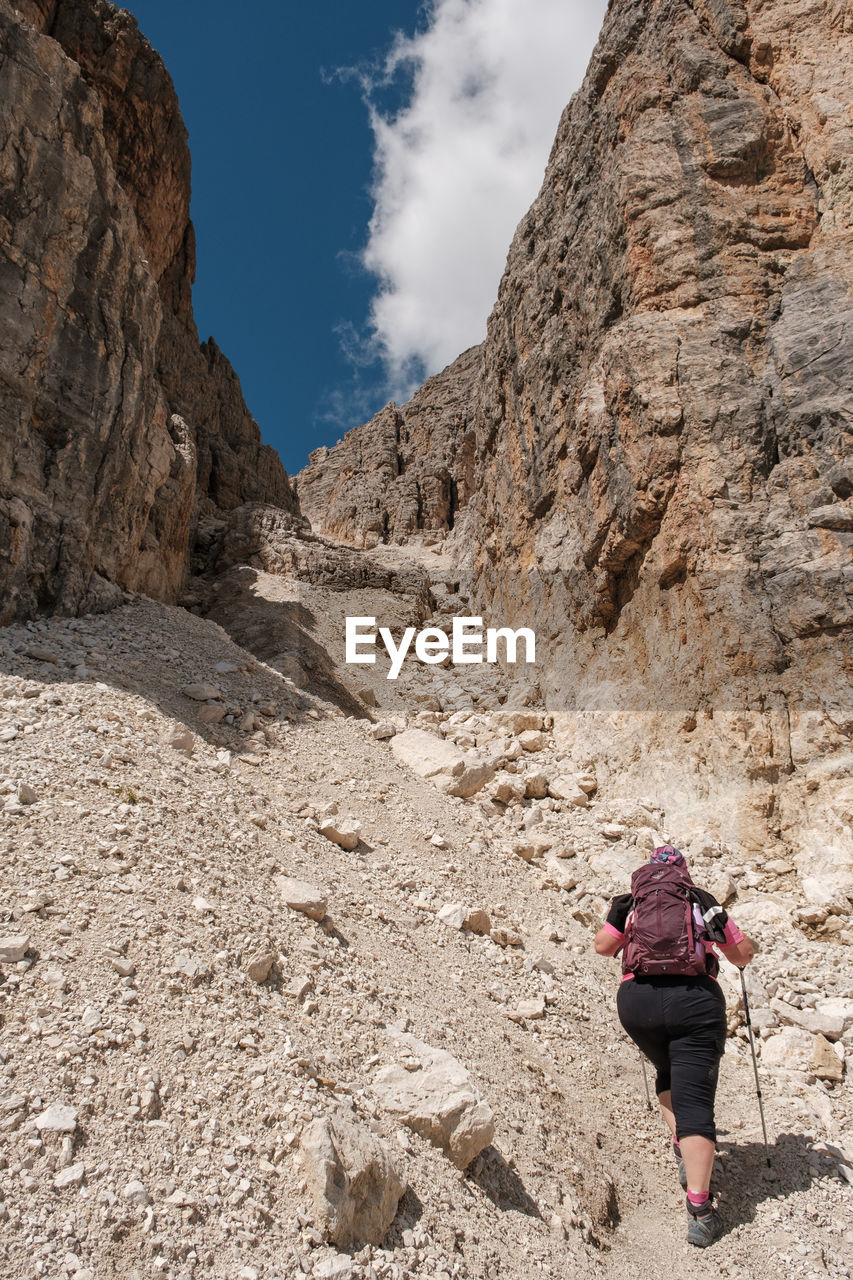 Rear view of woman walking on rock in mountains