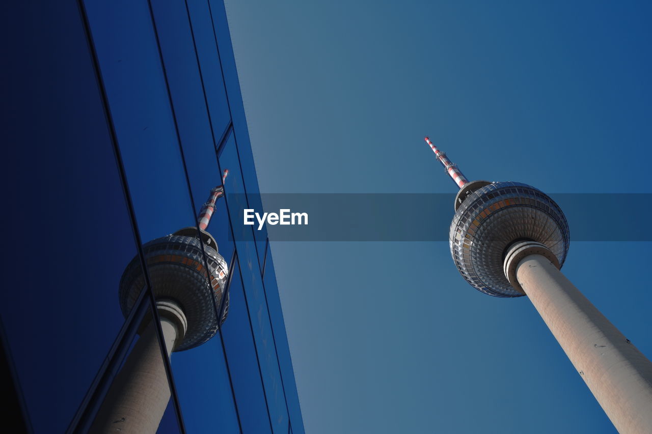 Low angle view of television tower against sky with reflection of a building