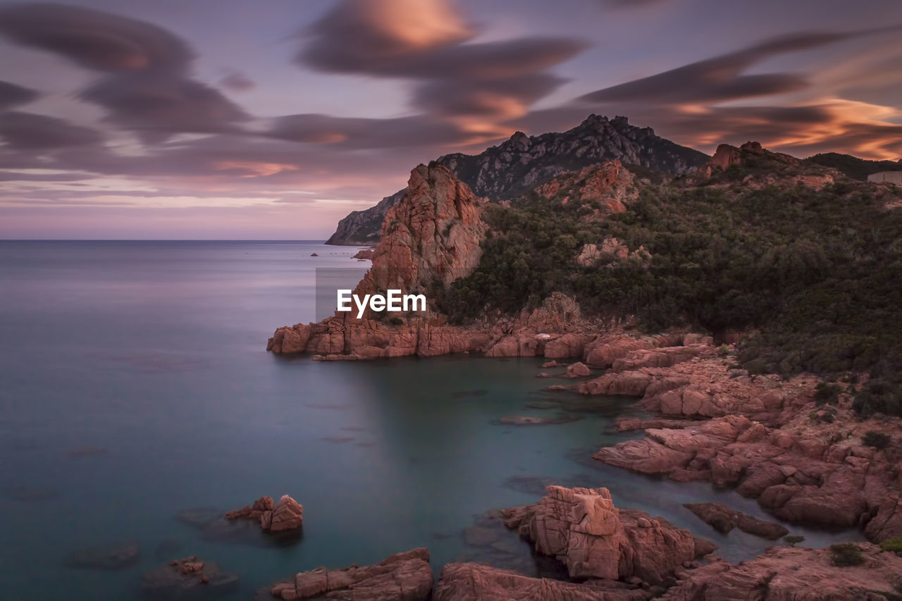 Scenic view of rock formations by sea against sky during sunset