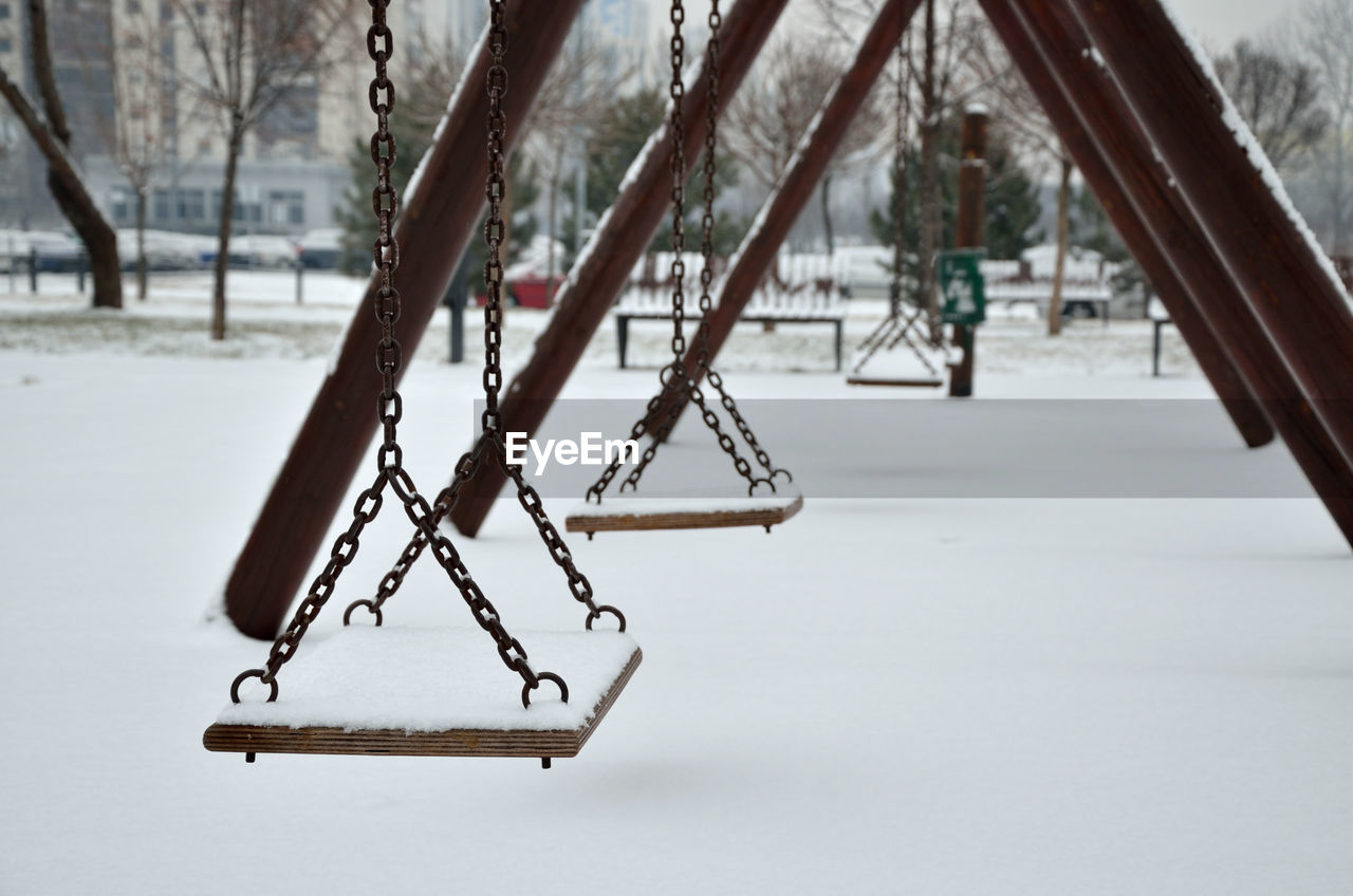Several swings in city park covered with snow