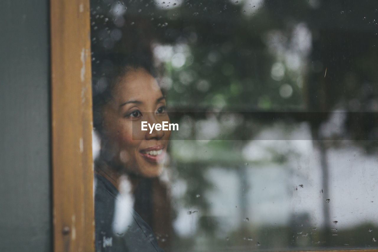 YOUNG WOMAN SEEN THROUGH WINDOW GLASS