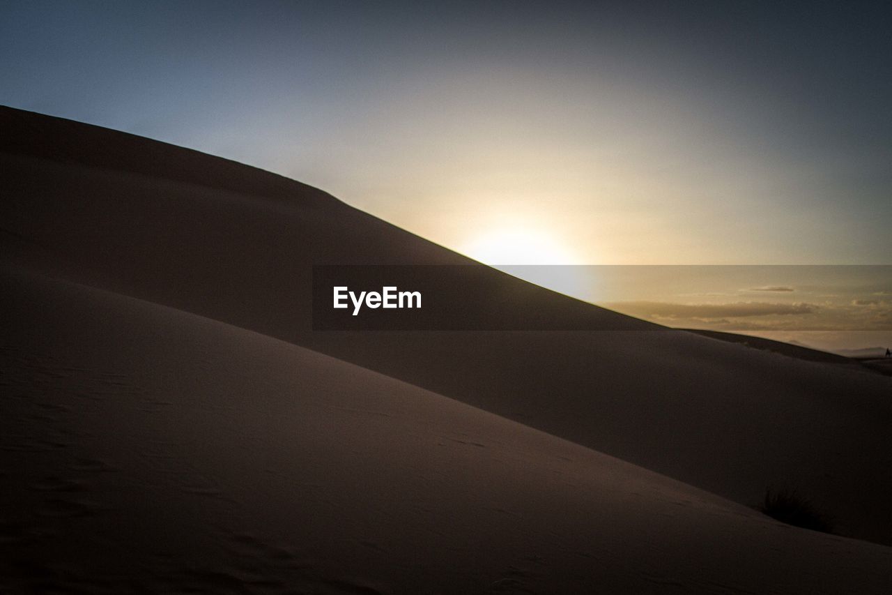 Scenic view of desert against sky at sunset