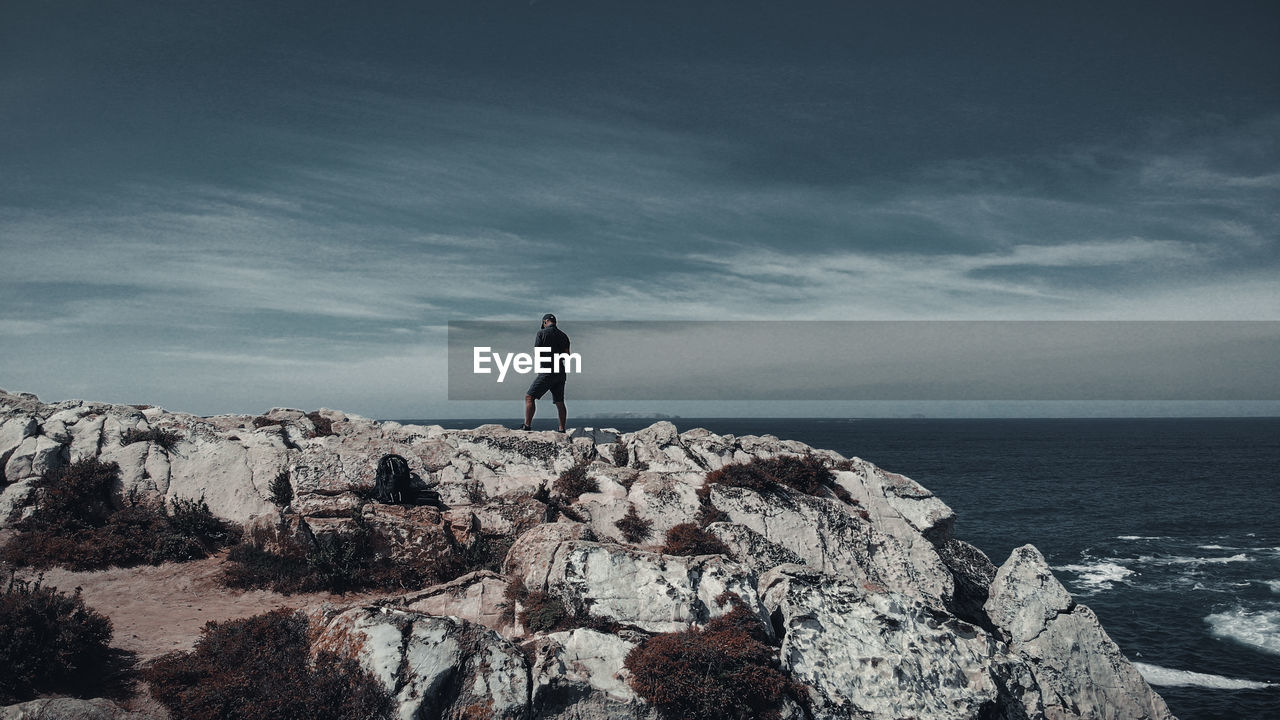 MAN LOOKING AT SEA AGAINST SKY