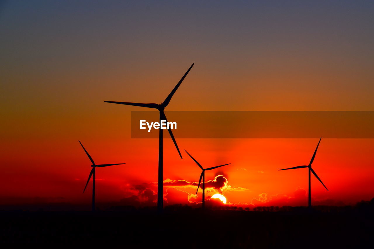 SILHOUETTE WINDMILLS ON FIELD AGAINST SKY DURING SUNSET