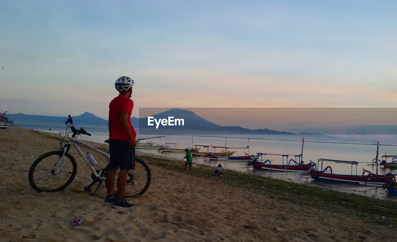 MAN WITH BICYCLE ON BEACH