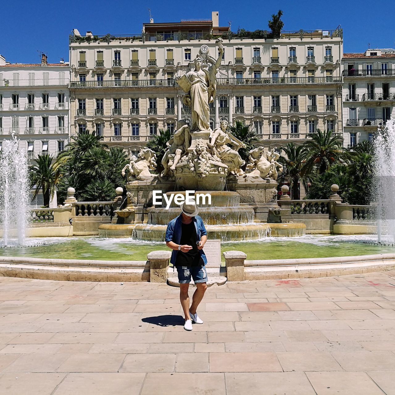 Man standing by fountain on sunny day