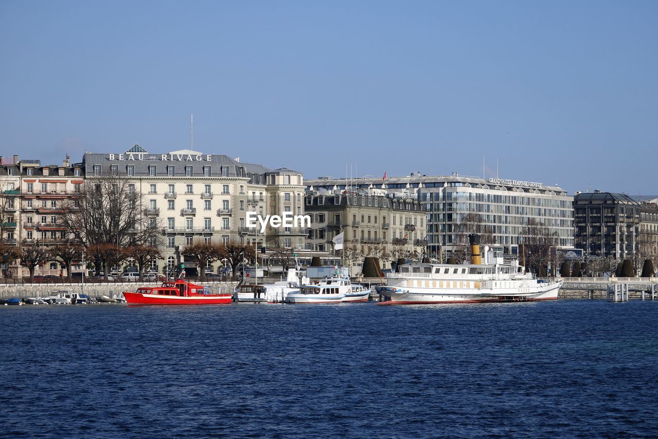 SAILBOAT IN SEA AGAINST BUILDINGS