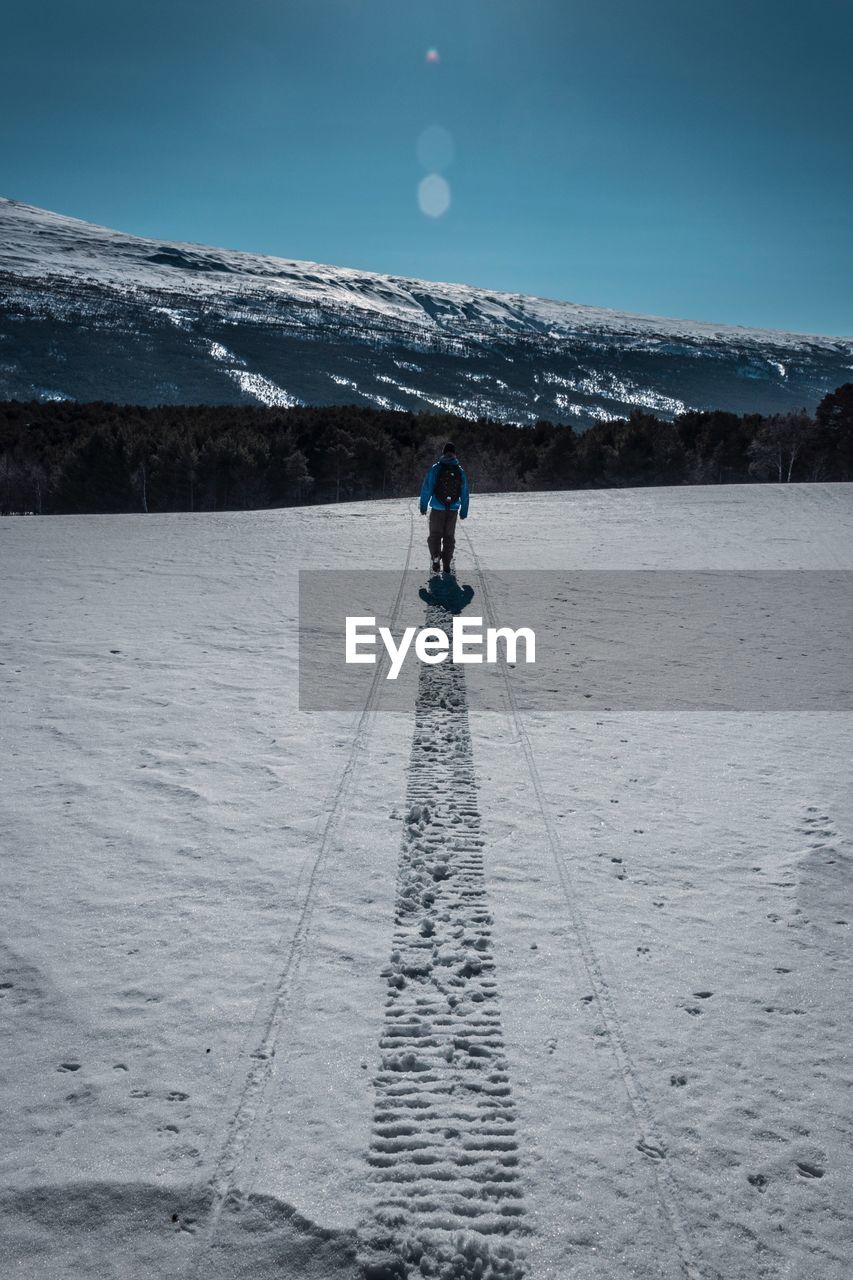 Rear view of person on snowcapped mountain against sky