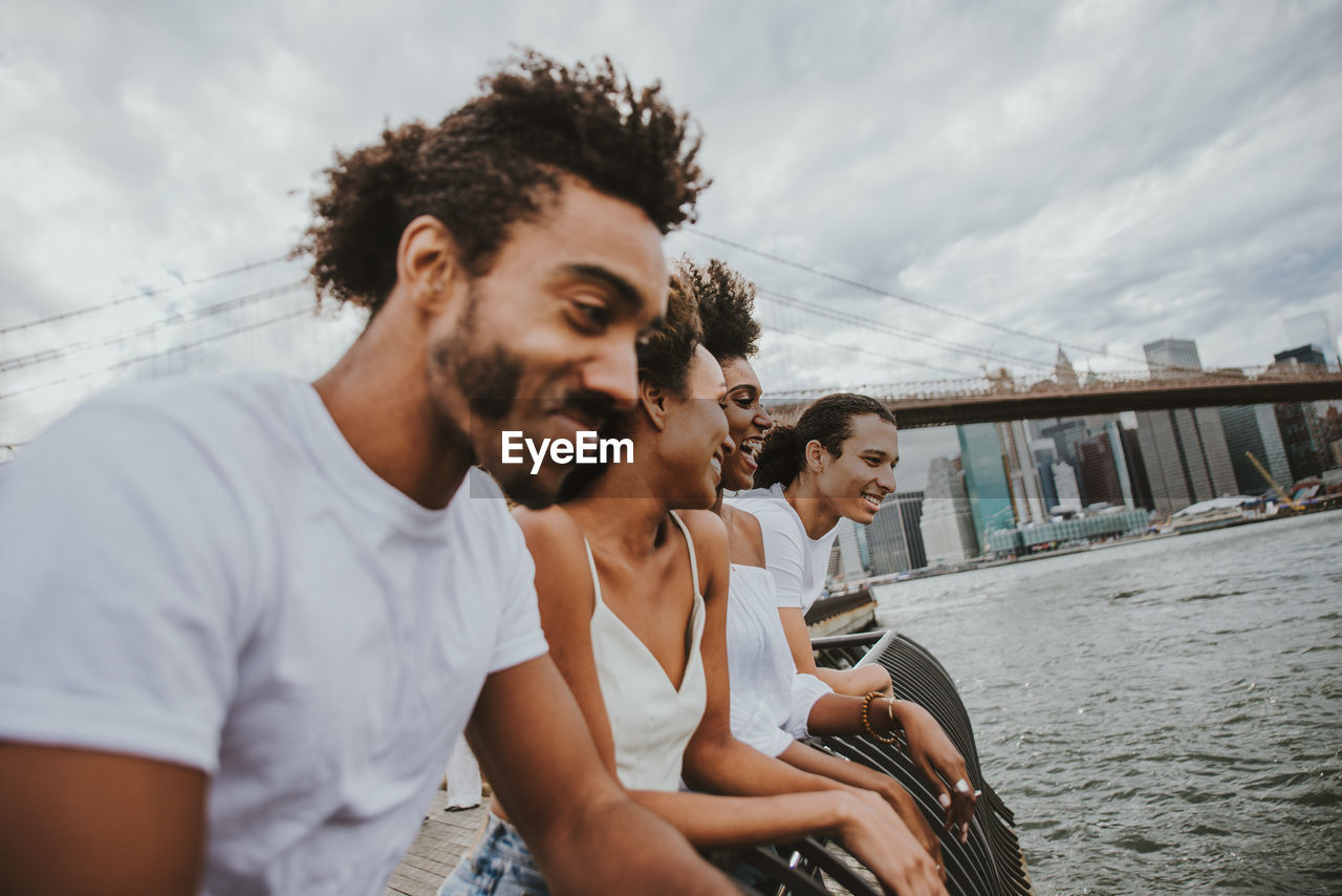 Friends sitting by east river in city