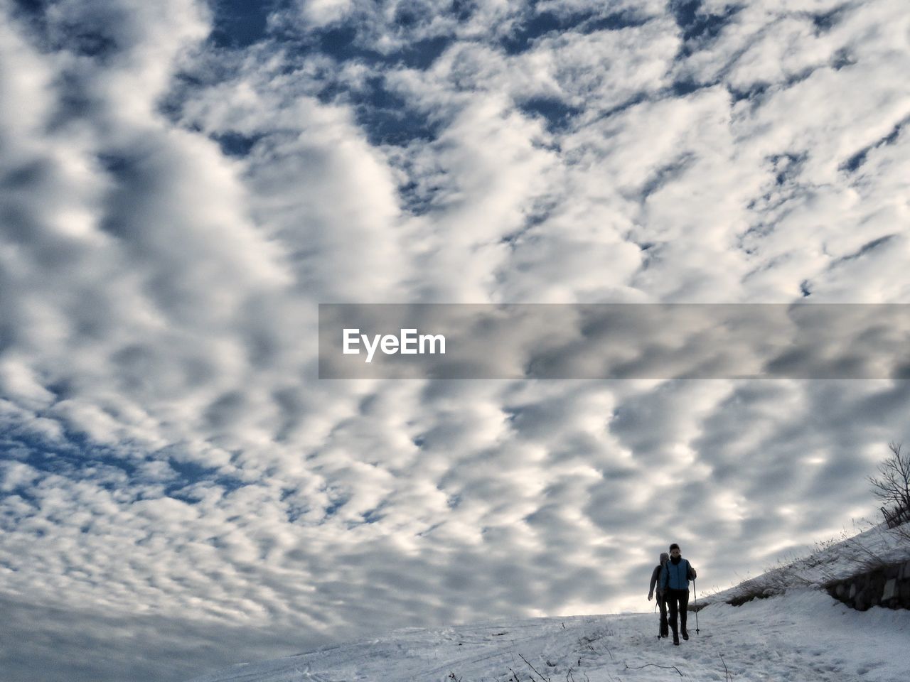 PEOPLE WALKING ON SNOWCAPPED MOUNTAIN AGAINST CLOUDY SKY