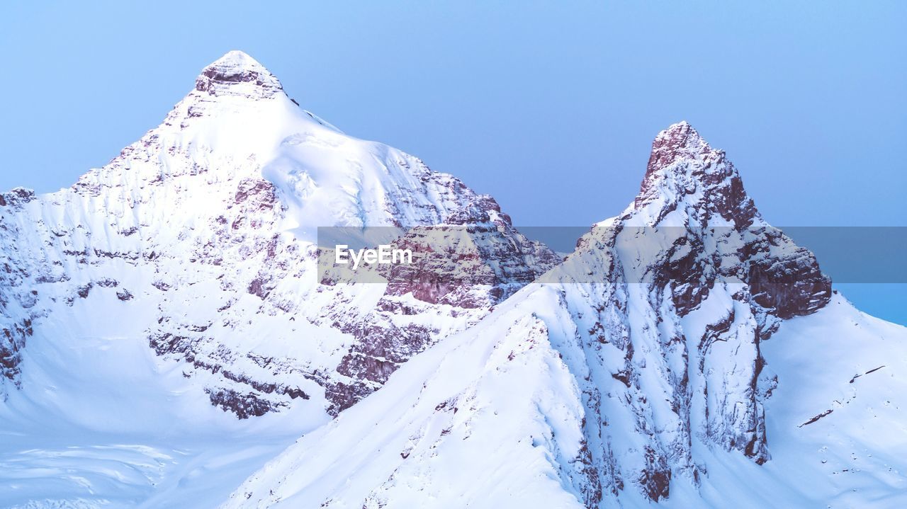 Aerial view of snowcapped mountains against clear blue sky