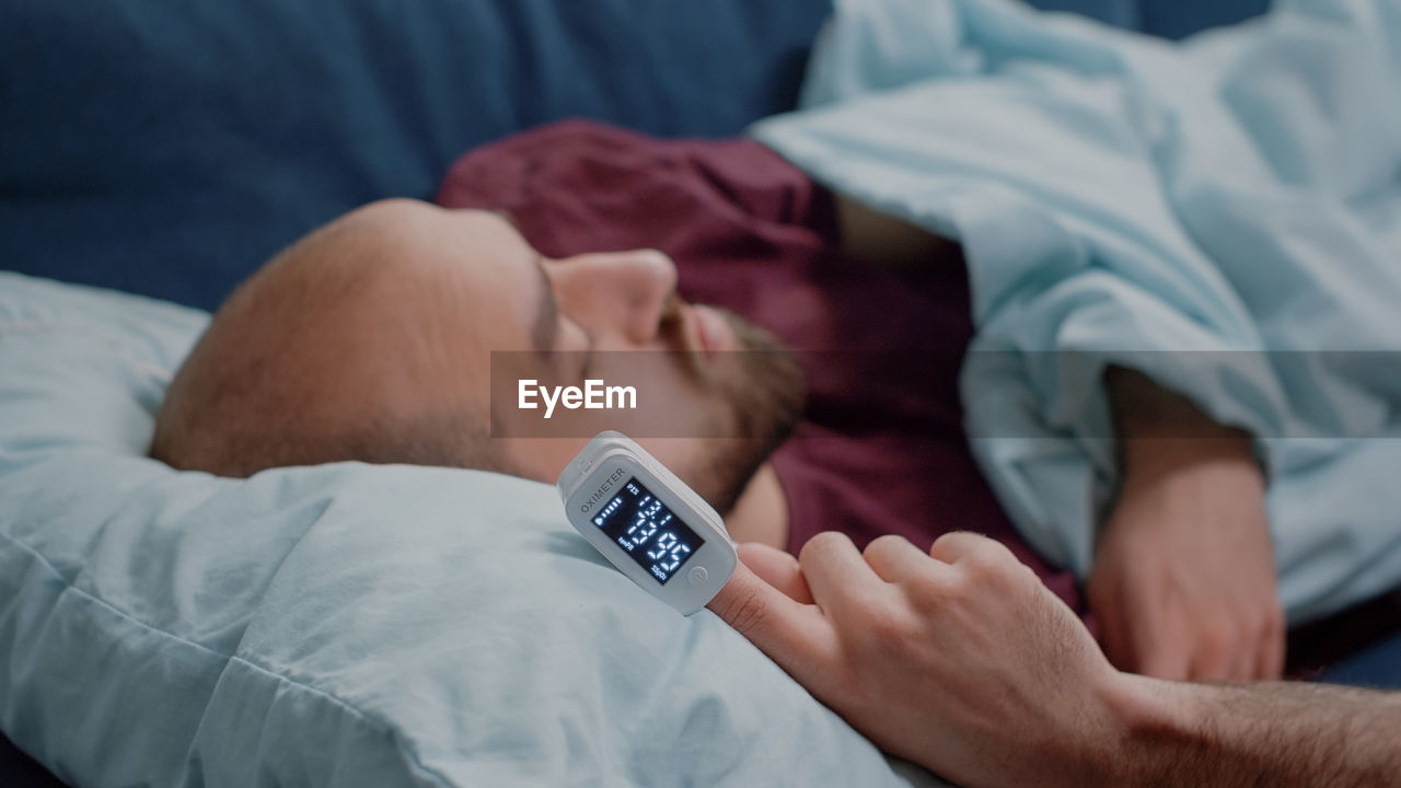 MIDSECTION OF MAN SLEEPING ON BED IN BLANKET