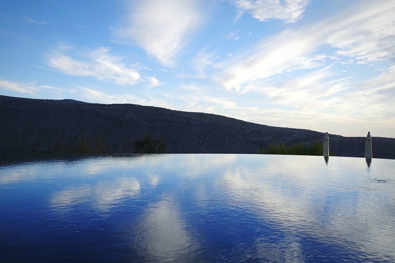 Scenic view of infinity pool by mountain against sky