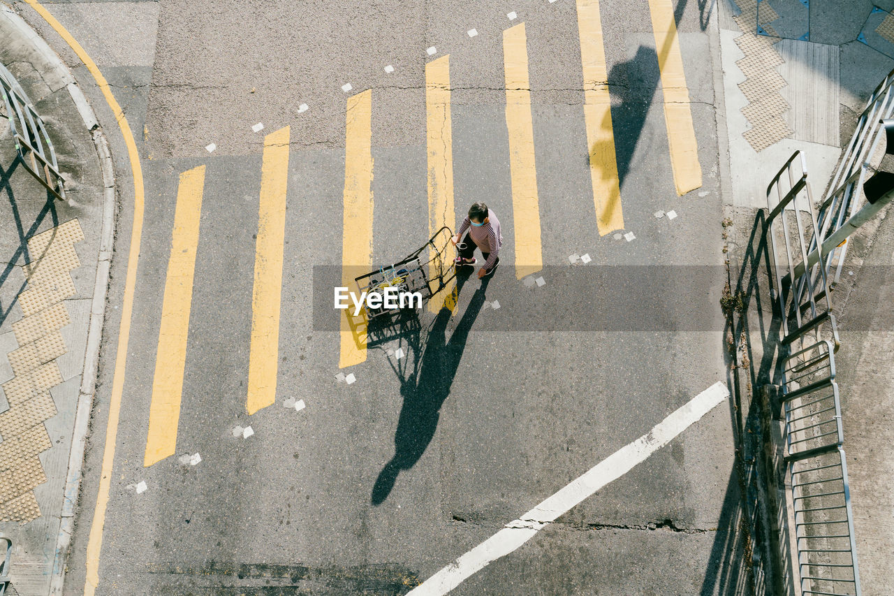 HIGH ANGLE VIEW OF MAN RIDING BICYCLE ON STREET