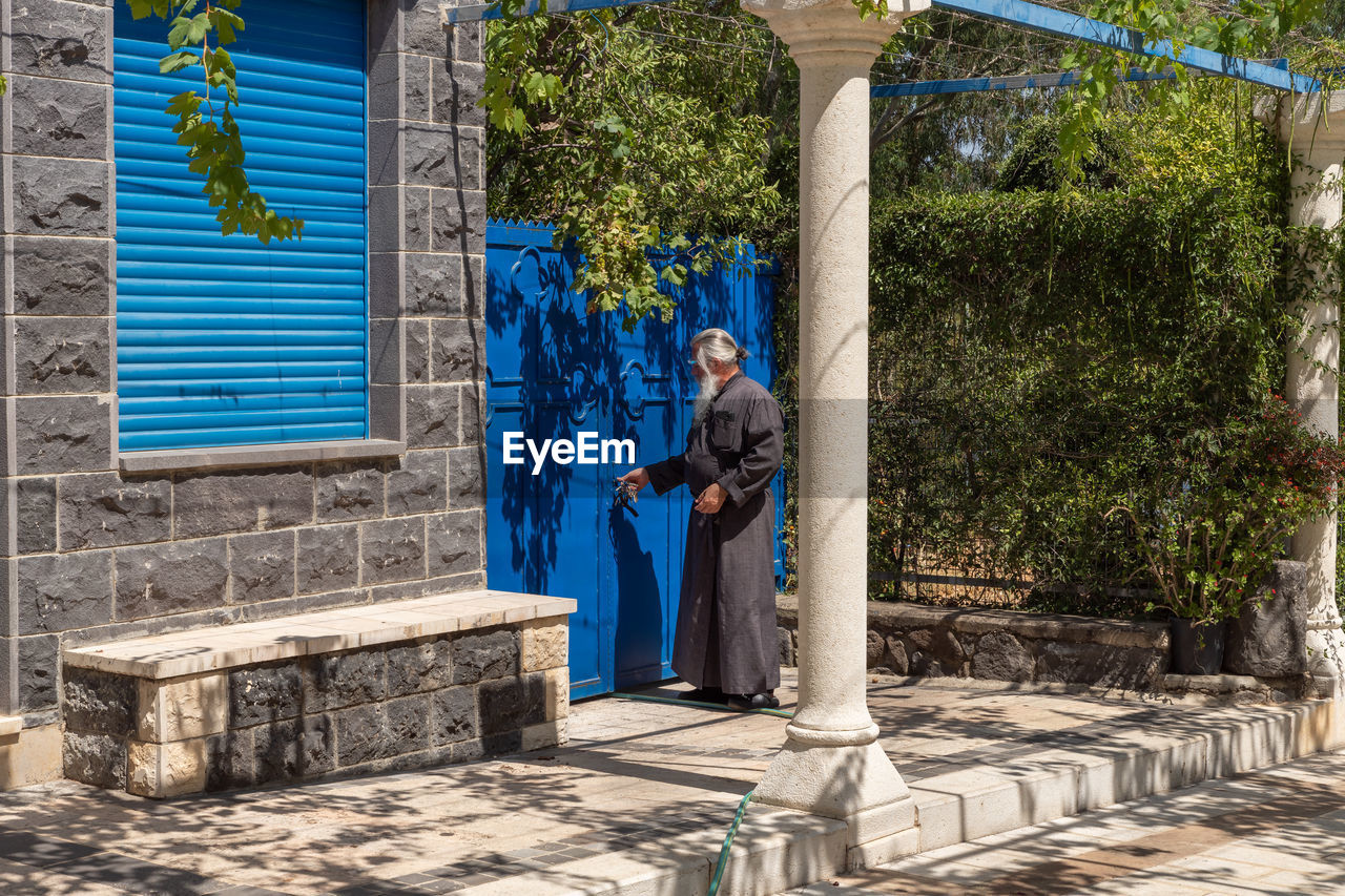 MAN STANDING AGAINST BLUE BUILDING