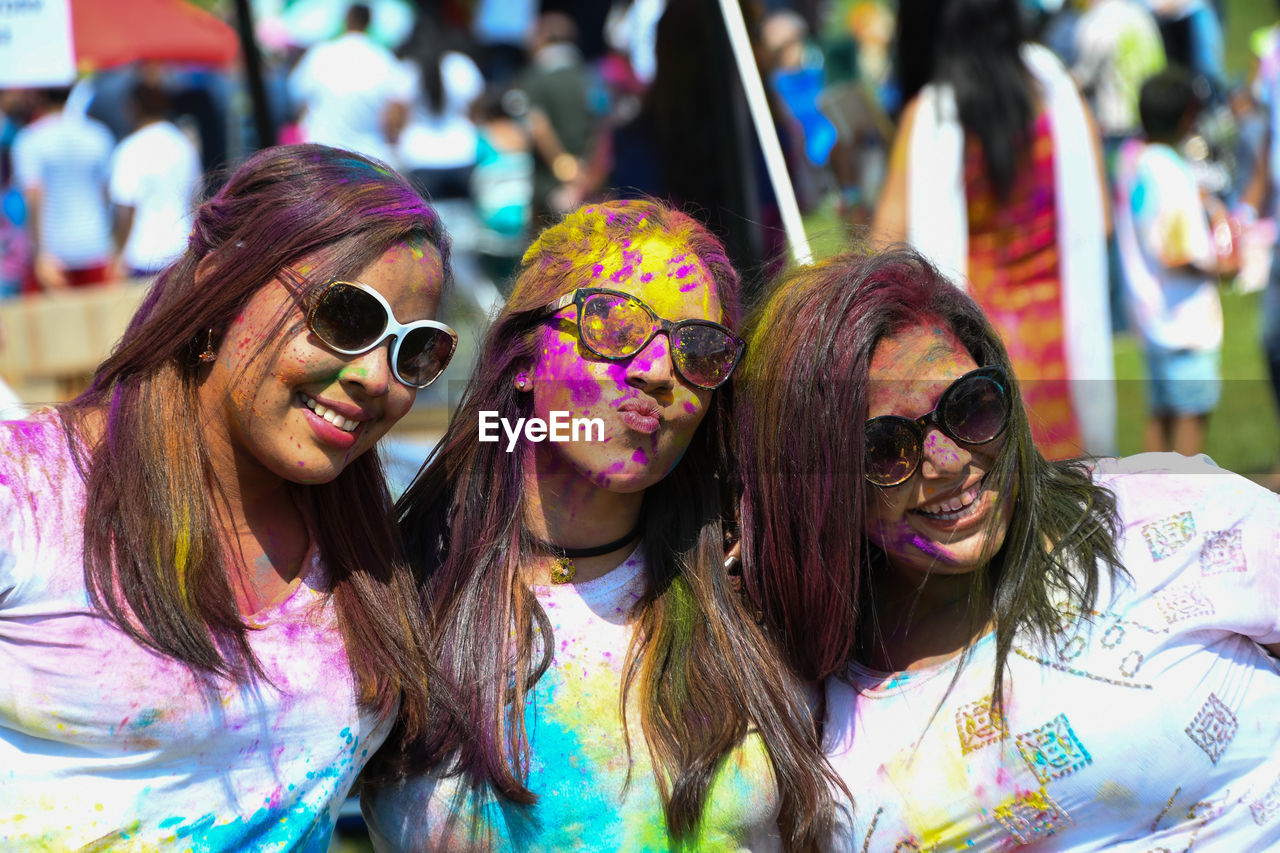 PORTRAIT OF SMILING YOUNG WOMAN WEARING SUNGLASSES OUTDOORS