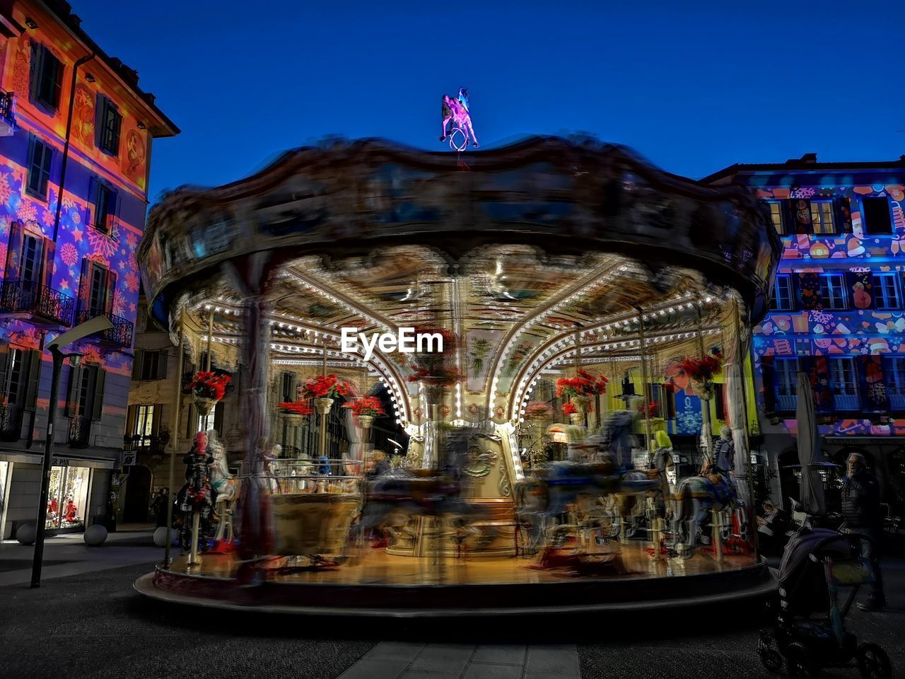 People in amusement park against clear sky at night