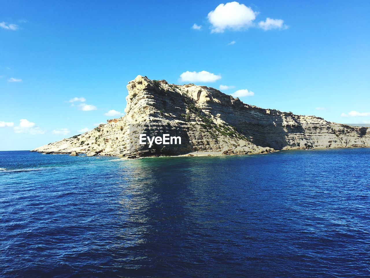 Scenic view of sea by mountain against sky