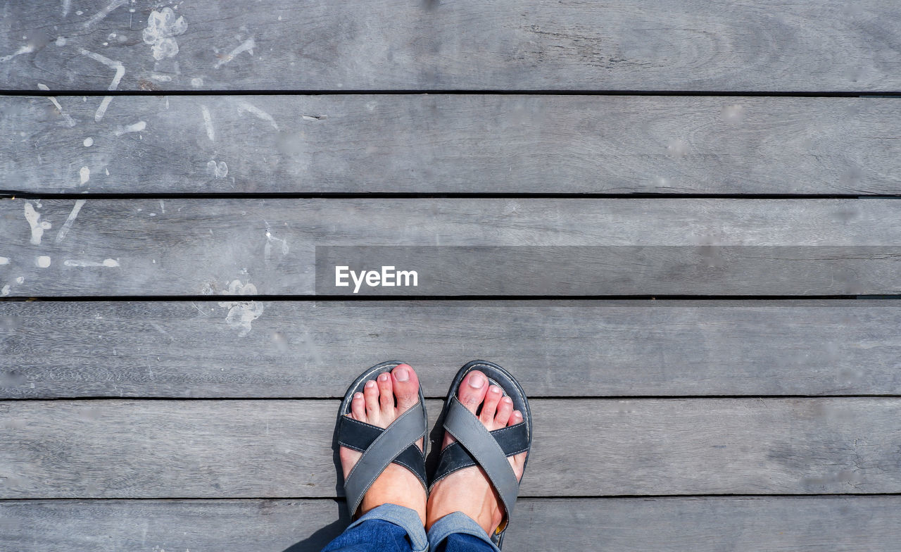 Low section of person standing on wooden floor