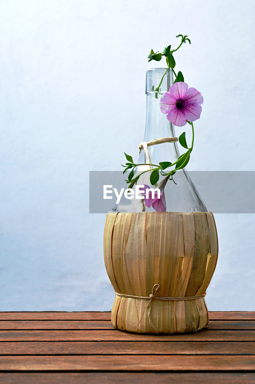 FLOWERS IN VASE ON TABLE AGAINST WALL