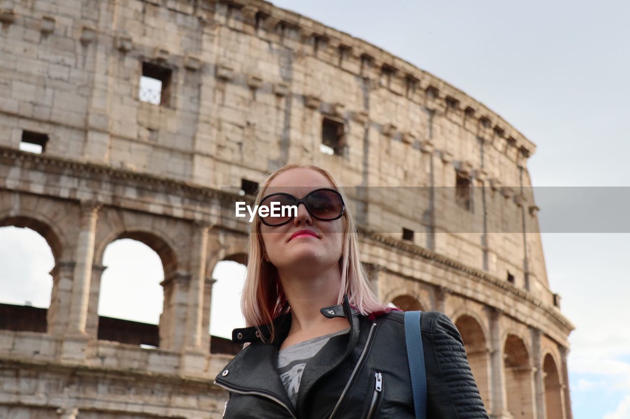Mid adult woman wearing sunglasses against coliseum