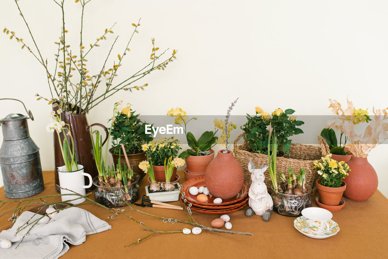 Easter holiday decor. daffodils and hyacinths in a pot, eggs and a rabbit figurine and branches