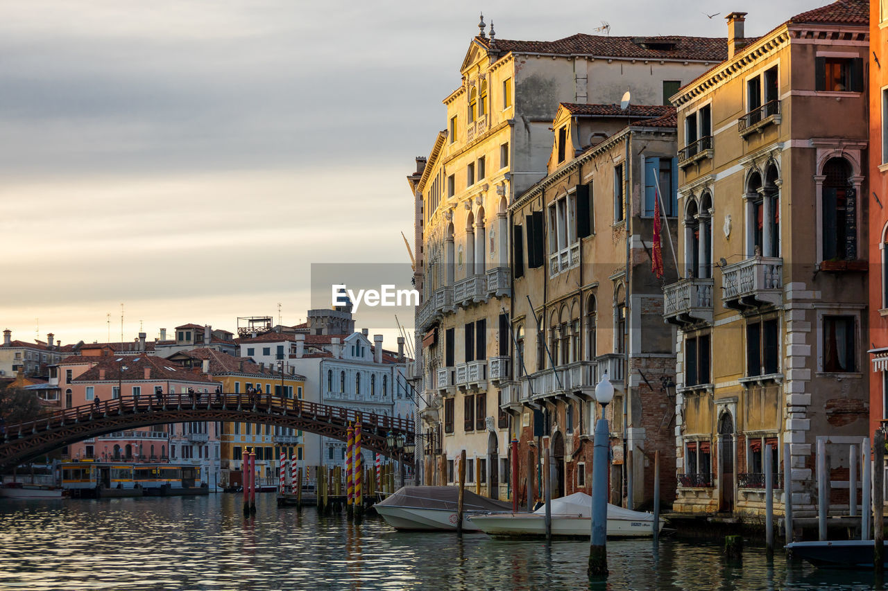 Canal amidst buildings against sky during sunset