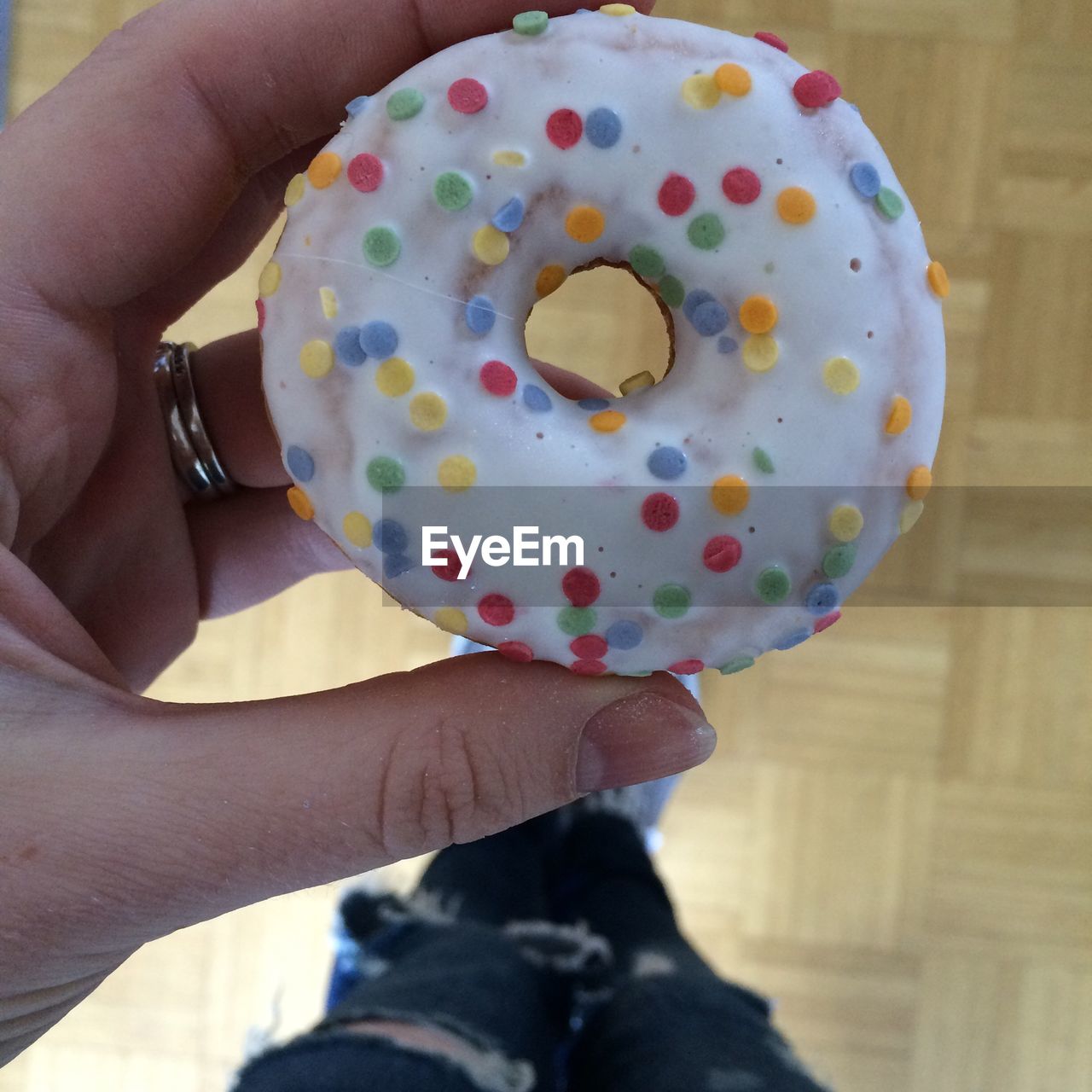 Low section of woman holding donut on hardwood floor