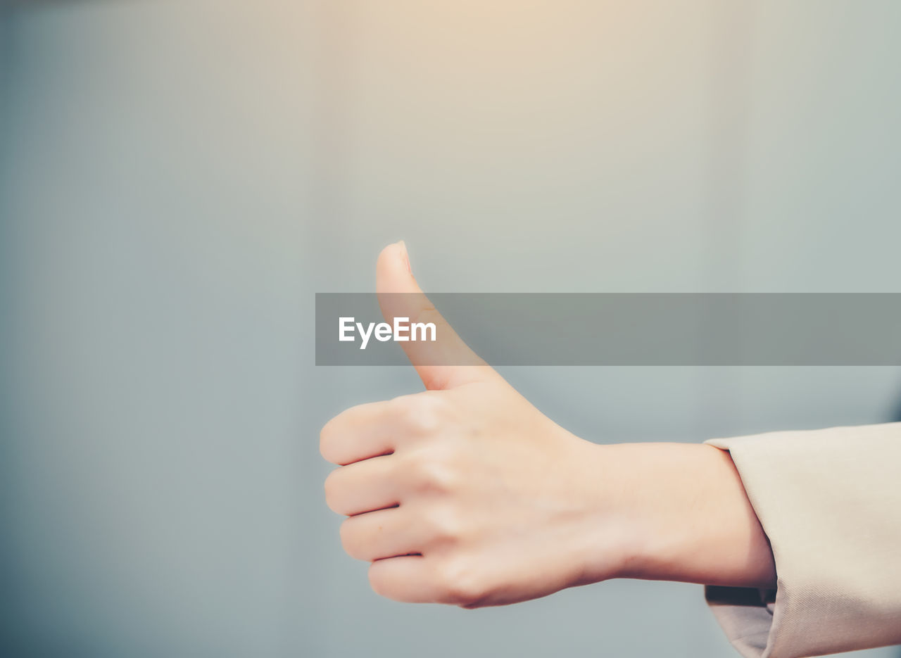 Cropped hand of businesswoman showing thumbs up