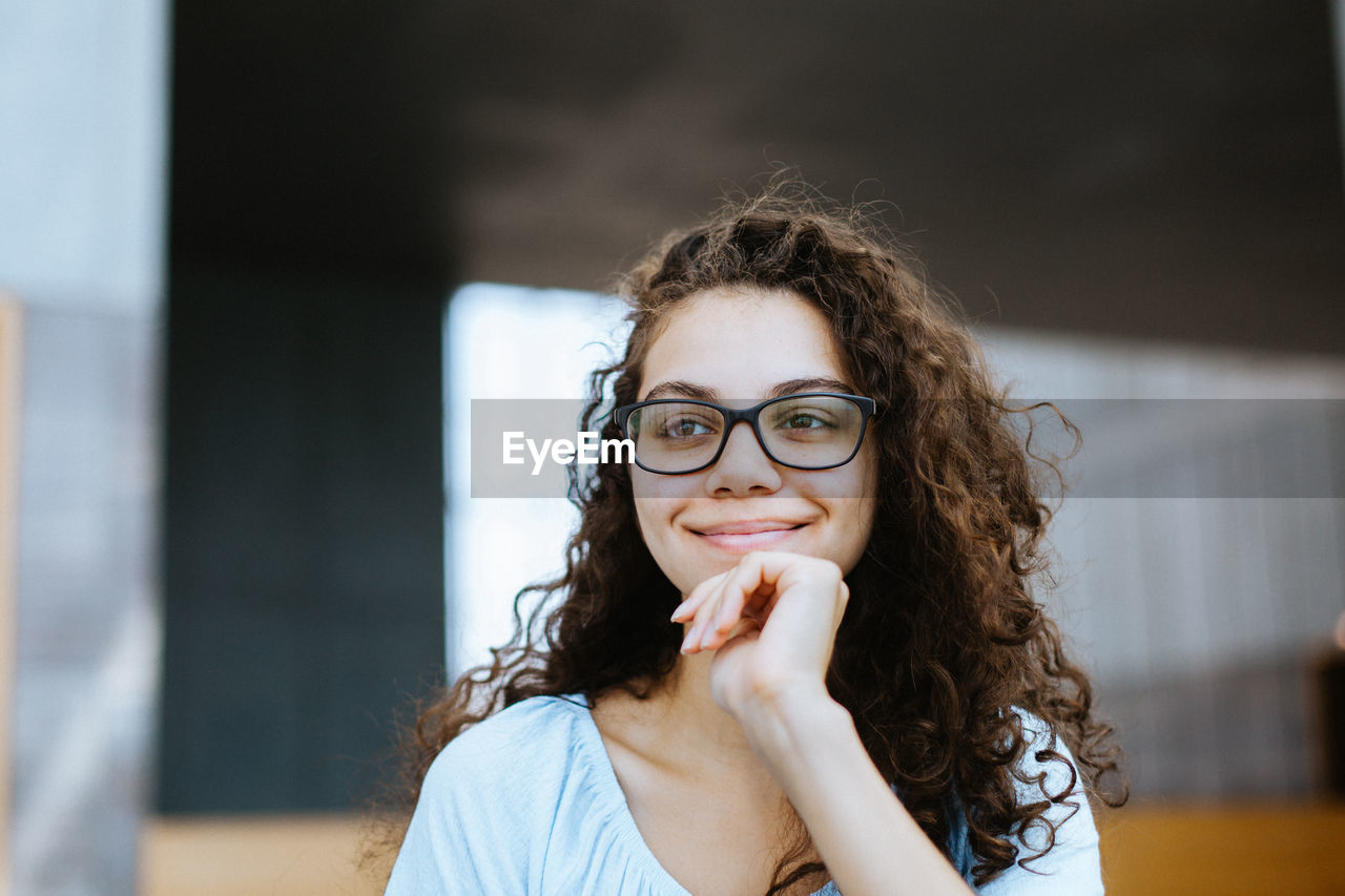 Close-up of thoughtful smiling woman against window