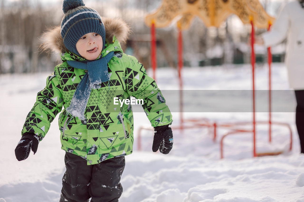 Portrait little boy walks on the playground on frosty winter day.