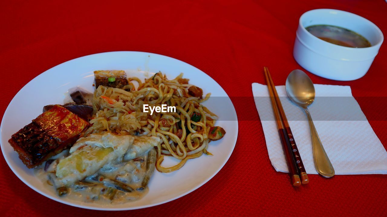 food and drink, food, plate, meal, dish, healthy eating, table, freshness, cuisine, pasta, eating utensil, wellbeing, drink, lunch, no people, fork, kitchen utensil, italian food, red, seafood, high angle view, restaurant, indoors, household equipment, tableware, asian food, meat, colored background, fried, crockery, refreshment, dinner, serving size, still life, red background, thai food, coffee cup, spaghetti