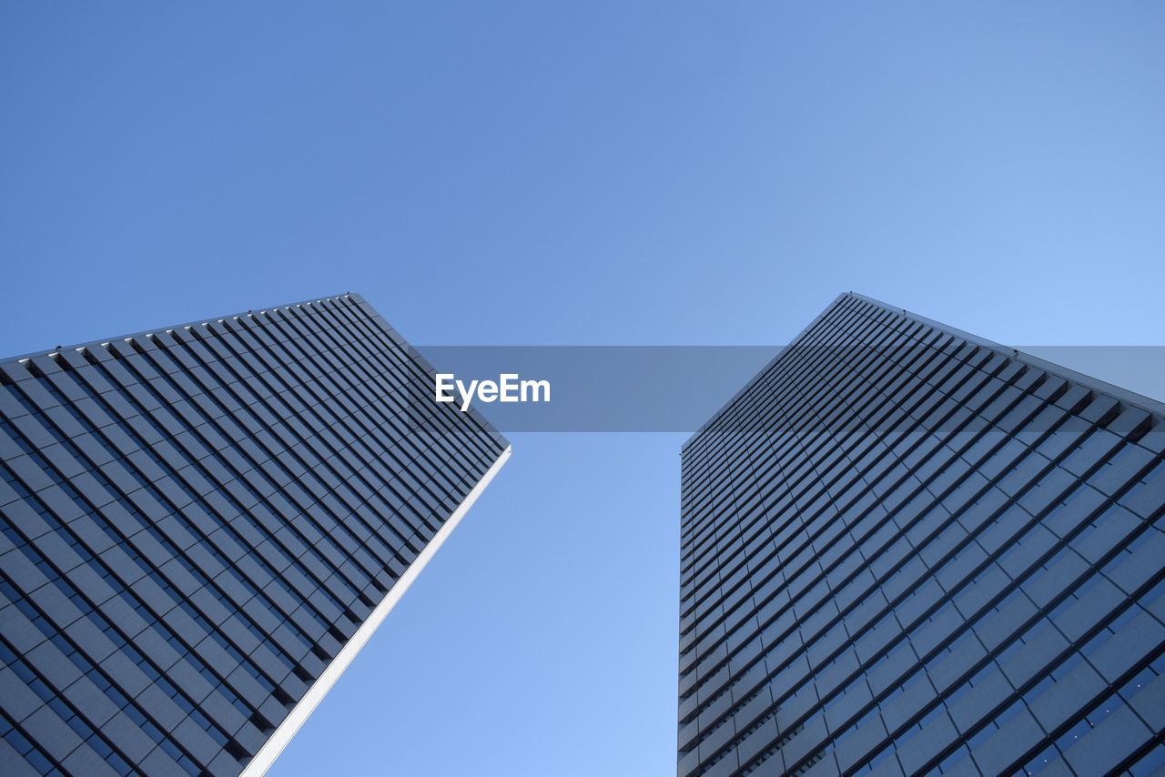 Tilted view of glass buildings against clear sky