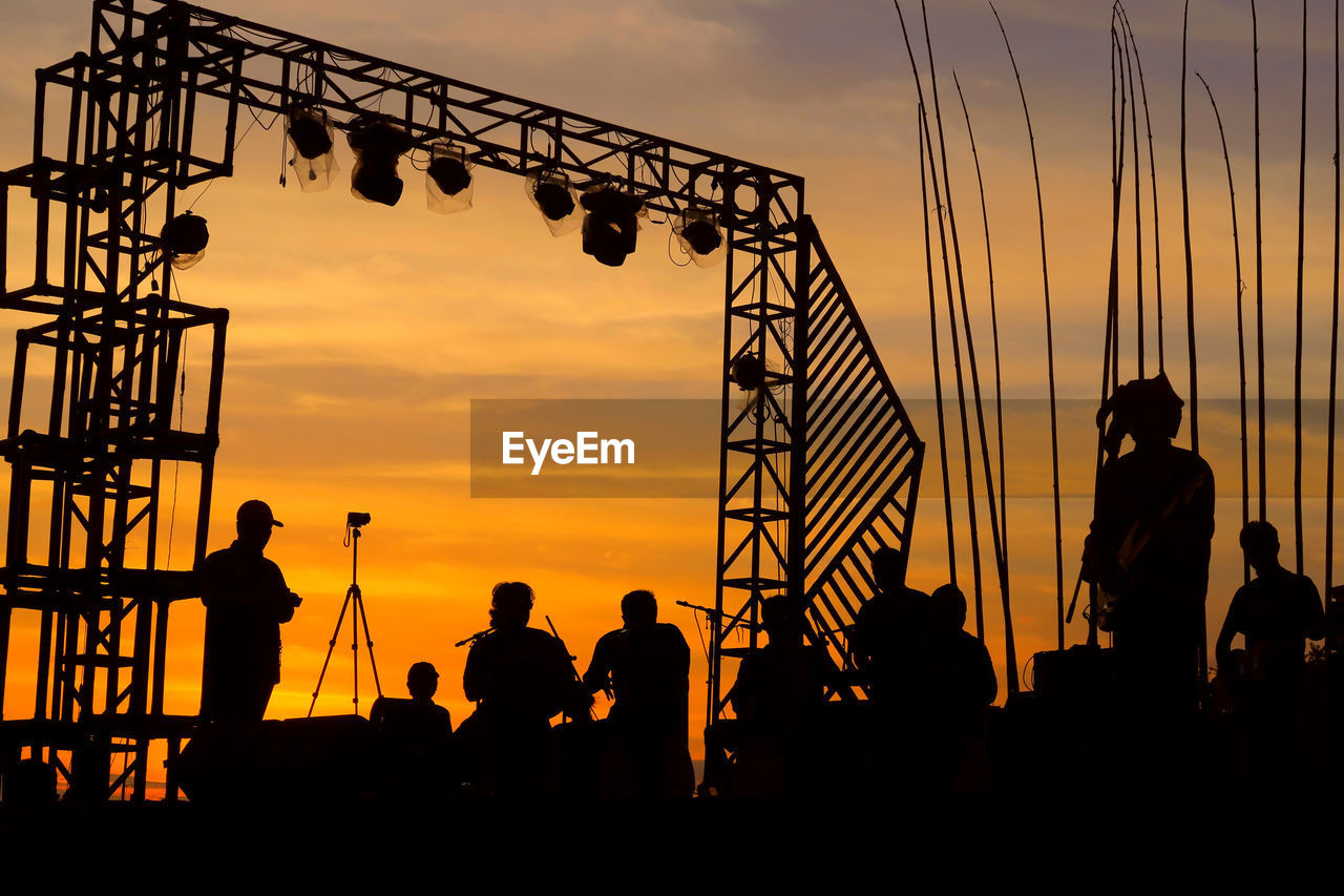 Silhouette of people performing on stage at sunset