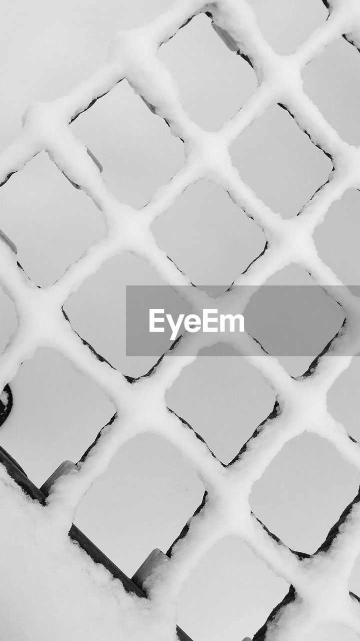 Low angle view of snow on metal grate against clear sky