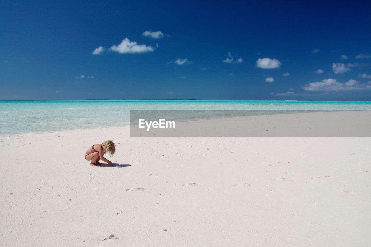 View of girl playing on beach against blue sky