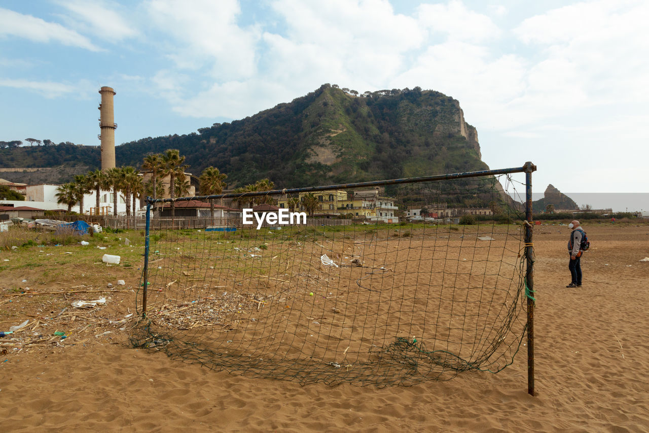 MAN ON BEACH AGAINST MOUNTAINS