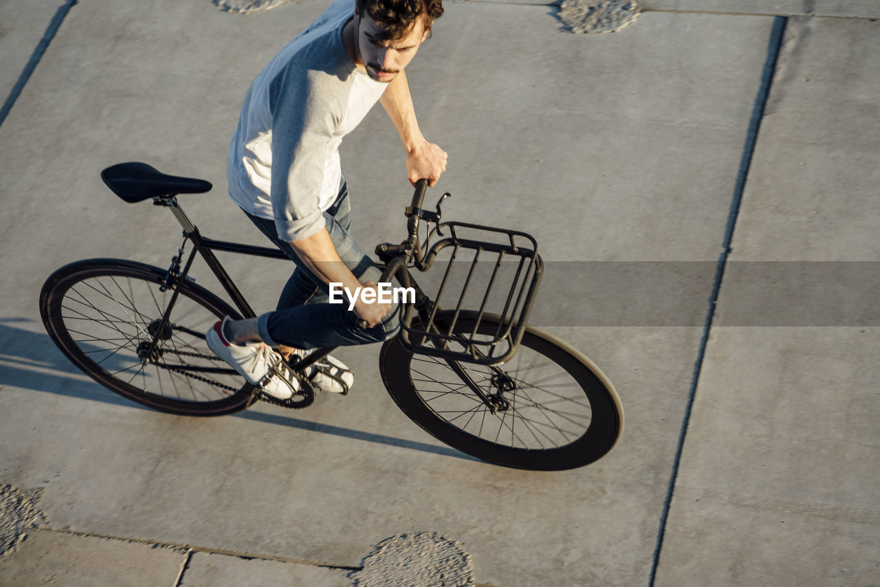Young man riding commuter fixie bike on concrete slabs