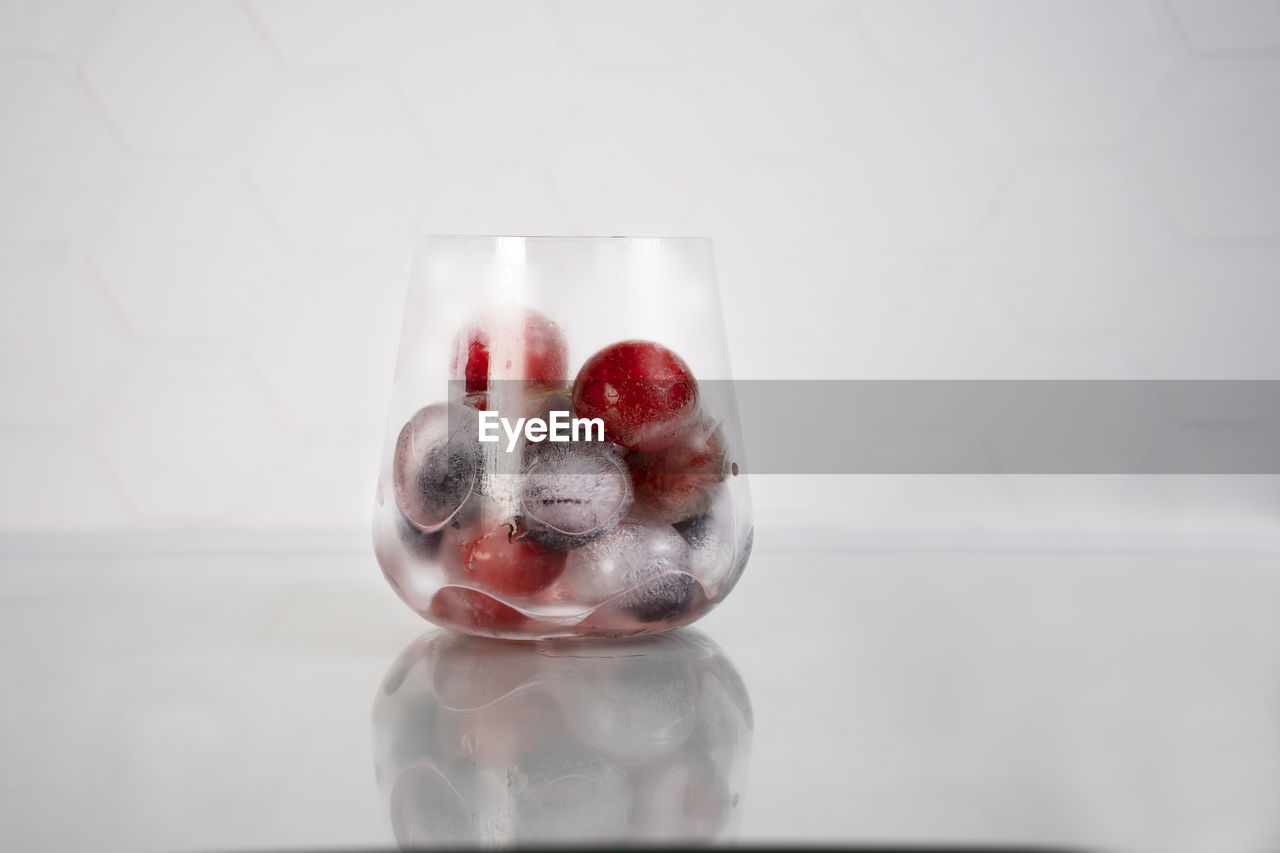 Frozen berries in ice cubes covered with hoarfrost in glass. homemade food. top view.