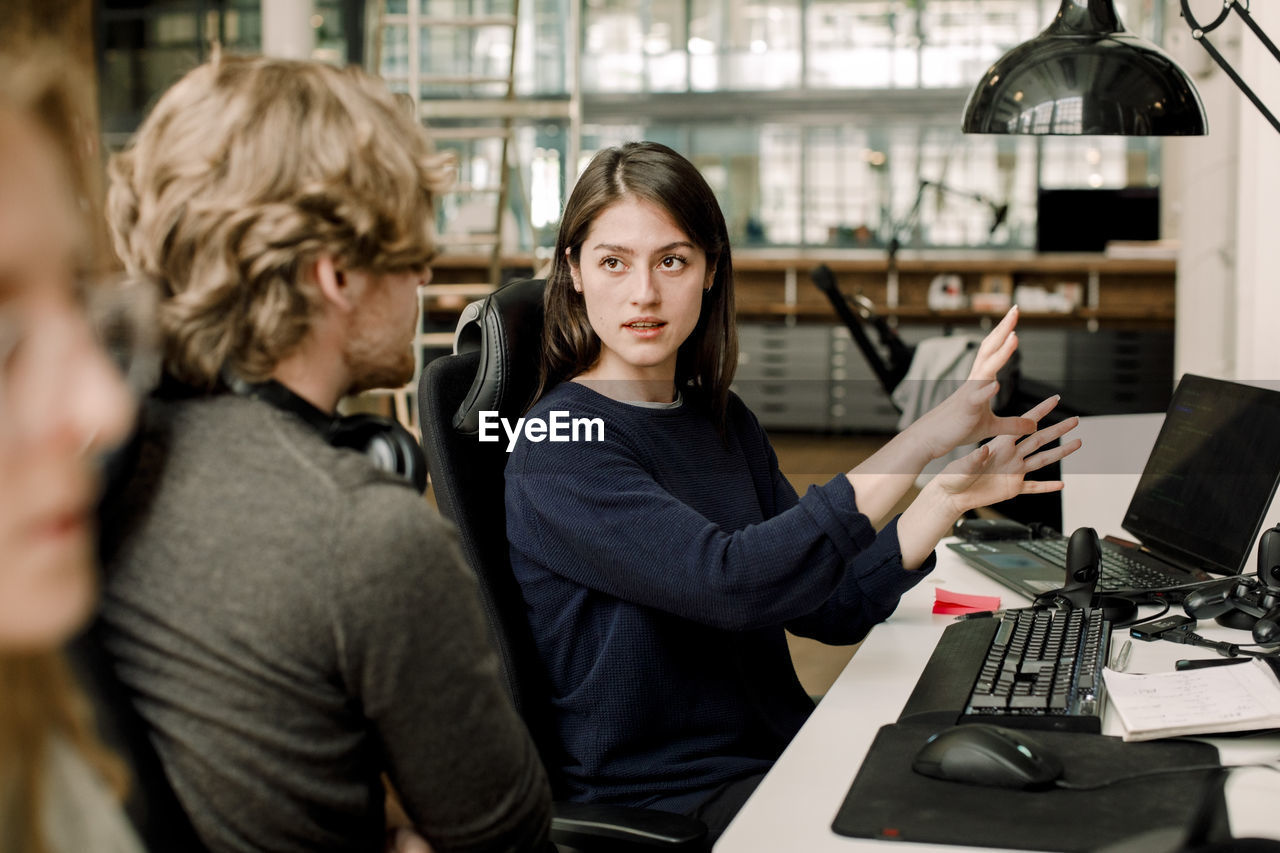 Entrepreneur explaining to colleague while sitting in office