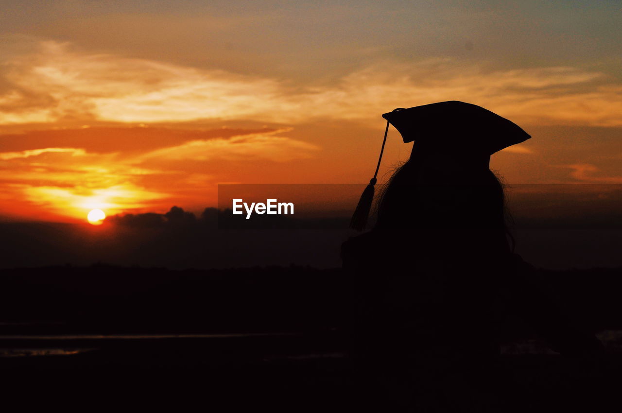 SILHOUETTE PERSON STANDING AGAINST ORANGE SKY